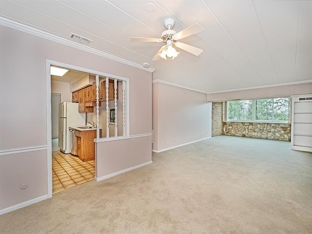 unfurnished living room with sink, ceiling fan, crown molding, and light carpet