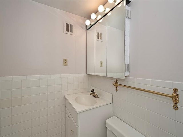 bathroom featuring vanity, toilet, and tile walls