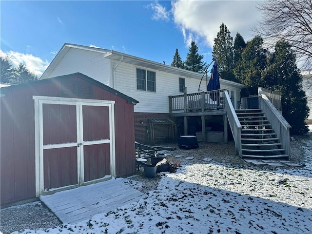 snow covered property with a storage unit and a wooden deck