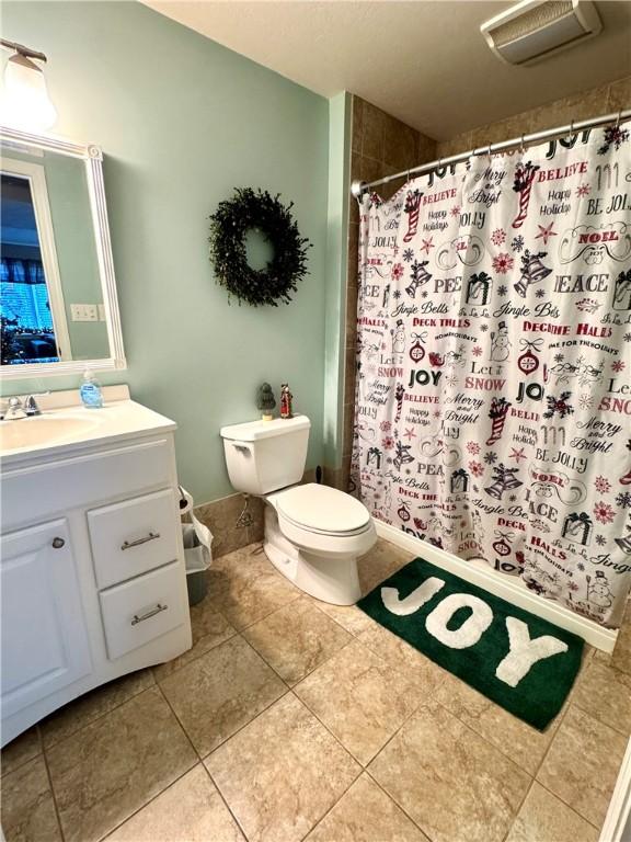 bathroom featuring tile patterned flooring, vanity, curtained shower, and toilet