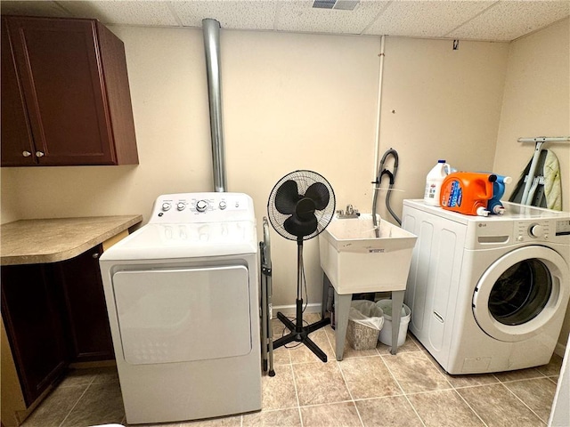 washroom with washer and dryer, light tile patterned floors, and cabinets