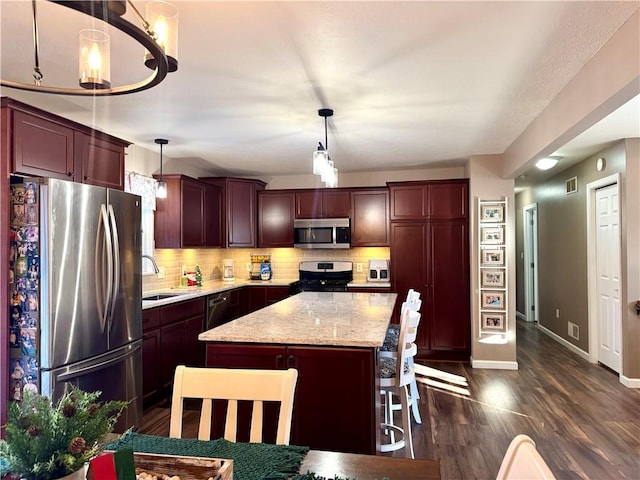 kitchen featuring decorative backsplash, a kitchen island, hanging light fixtures, and stainless steel appliances