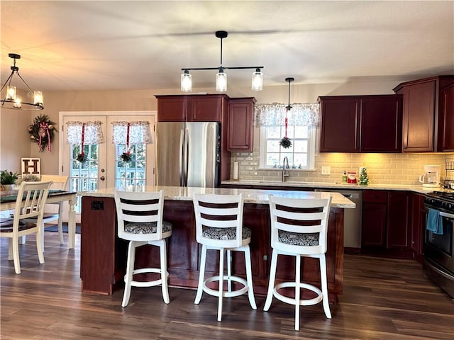 kitchen featuring dark hardwood / wood-style flooring, a center island, stainless steel appliances, and hanging light fixtures