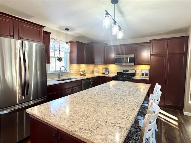 kitchen featuring stainless steel appliances, a kitchen island, hanging light fixtures, and sink