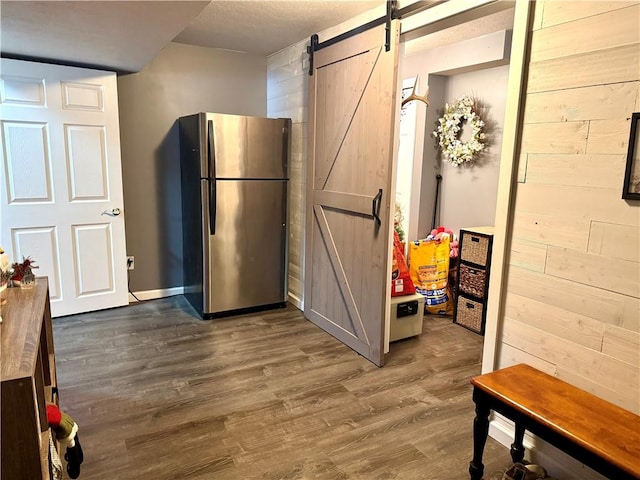 kitchen featuring stainless steel fridge, a barn door, and hardwood / wood-style floors