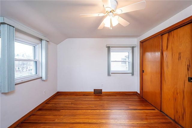 unfurnished bedroom featuring dark hardwood / wood-style floors, a closet, ceiling fan, and multiple windows