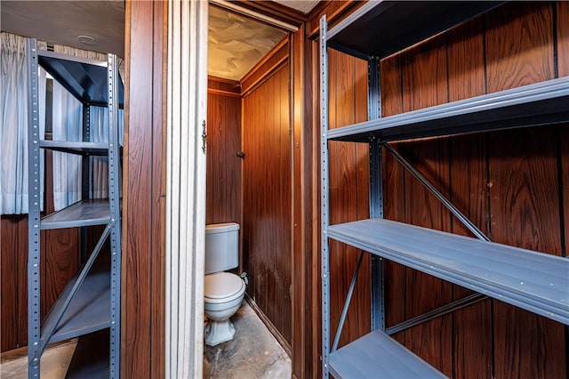 bathroom featuring toilet and wooden walls