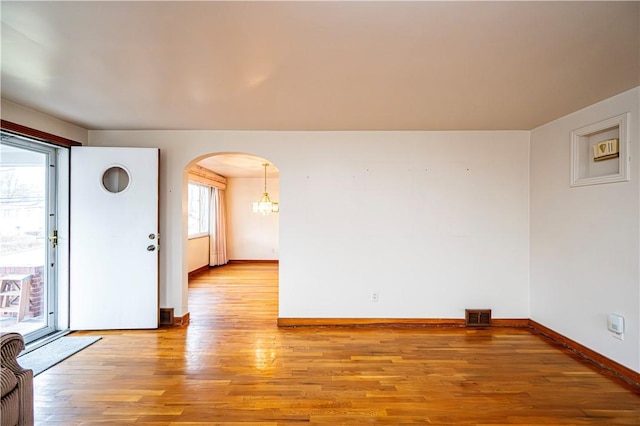 spare room featuring an inviting chandelier and light wood-type flooring