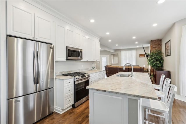 kitchen featuring white cabinets, stainless steel appliances, a center island with sink, and sink