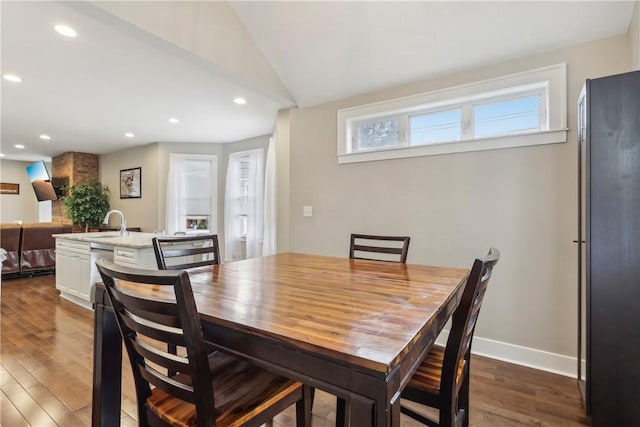 dining space with dark hardwood / wood-style flooring, sink, and vaulted ceiling