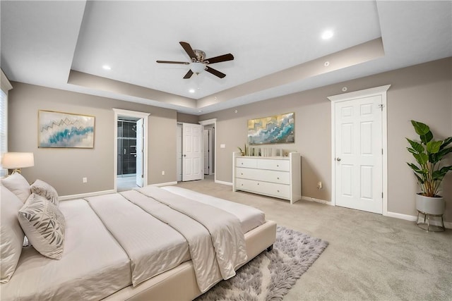 carpeted bedroom with a raised ceiling, ceiling fan, and ensuite bathroom