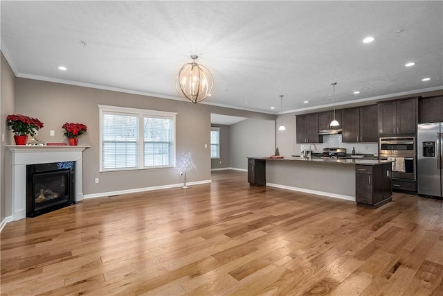 kitchen featuring a kitchen island with sink, light wood-type flooring, decorative light fixtures, dark brown cabinets, and stainless steel appliances