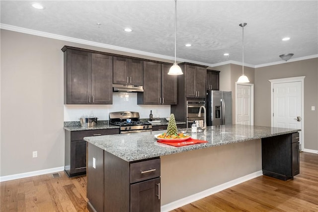 kitchen with stainless steel appliances, hanging light fixtures, and an island with sink