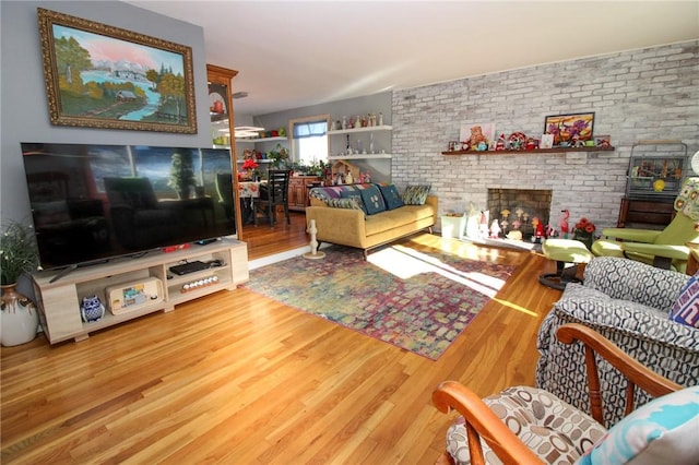 living room with wood-type flooring, brick wall, and a brick fireplace