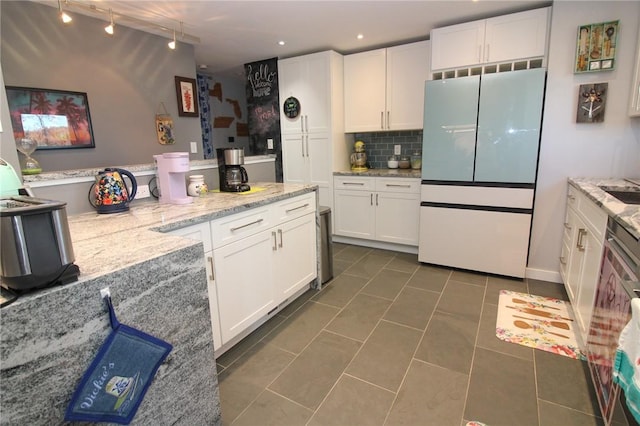 kitchen with white refrigerator, white cabinetry, backsplash, and dark tile patterned floors