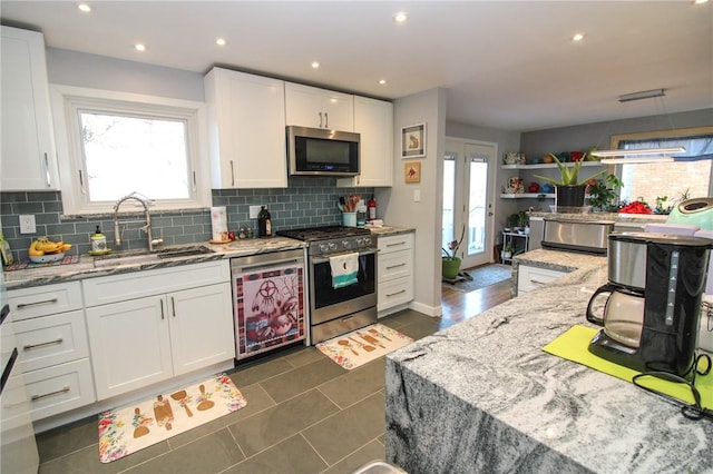 kitchen featuring light stone countertops, sink, stainless steel appliances, tasteful backsplash, and white cabinets