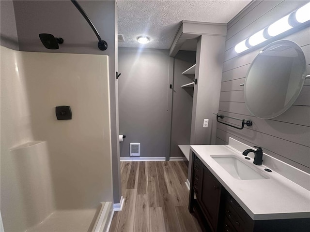 bathroom featuring hardwood / wood-style floors, vanity, a textured ceiling, and walk in shower