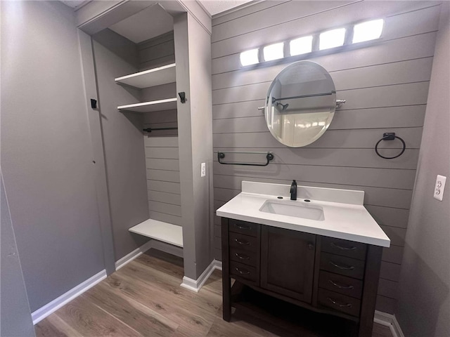 bathroom with wood walls, vanity, and wood-type flooring