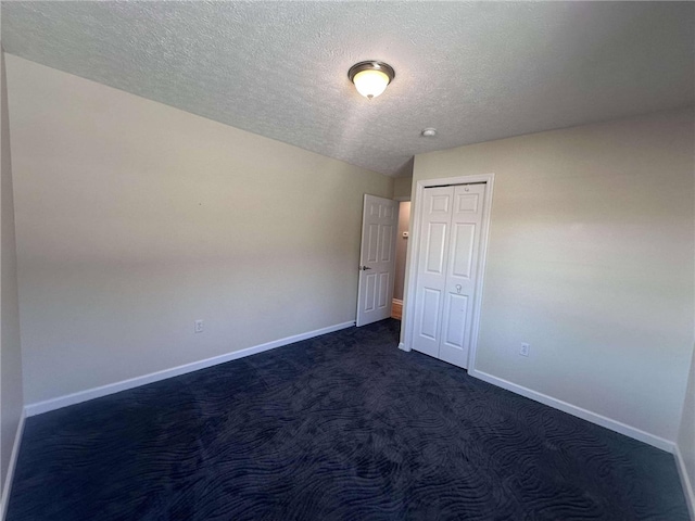 unfurnished bedroom featuring dark carpet and a textured ceiling