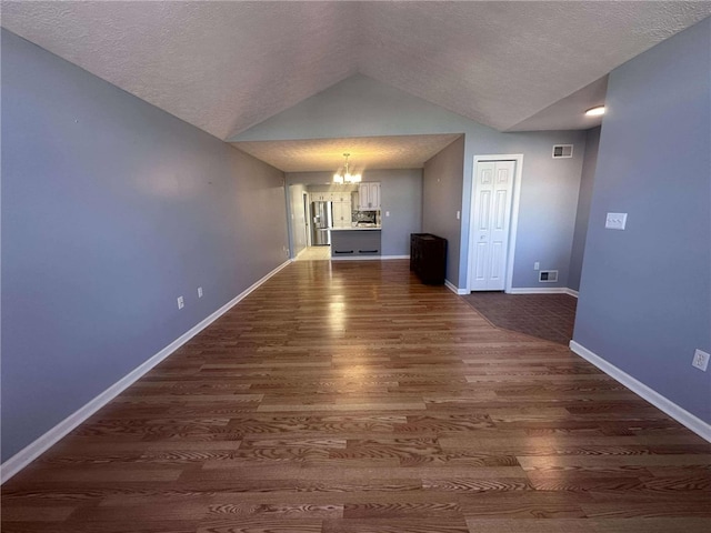 interior space with lofted ceiling, a textured ceiling, dark wood-type flooring, and a notable chandelier