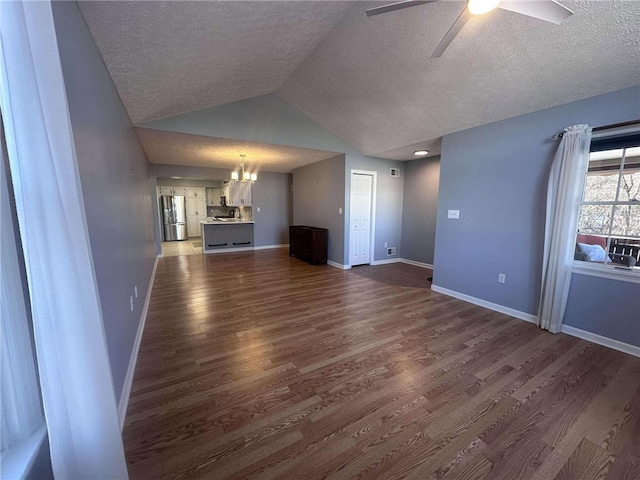 unfurnished living room featuring a textured ceiling, dark hardwood / wood-style flooring, ceiling fan with notable chandelier, and vaulted ceiling