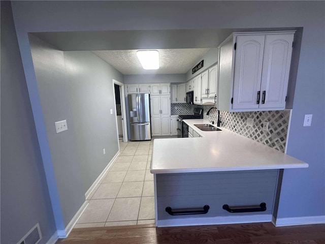 kitchen with white cabinetry, sink, kitchen peninsula, decorative backsplash, and appliances with stainless steel finishes