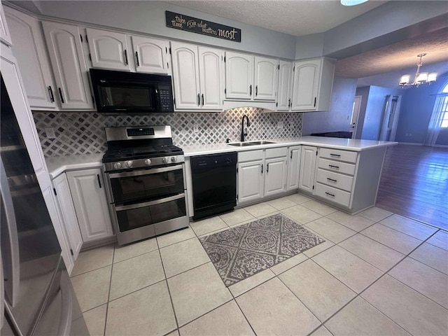 kitchen featuring sink, kitchen peninsula, pendant lighting, white cabinets, and black appliances