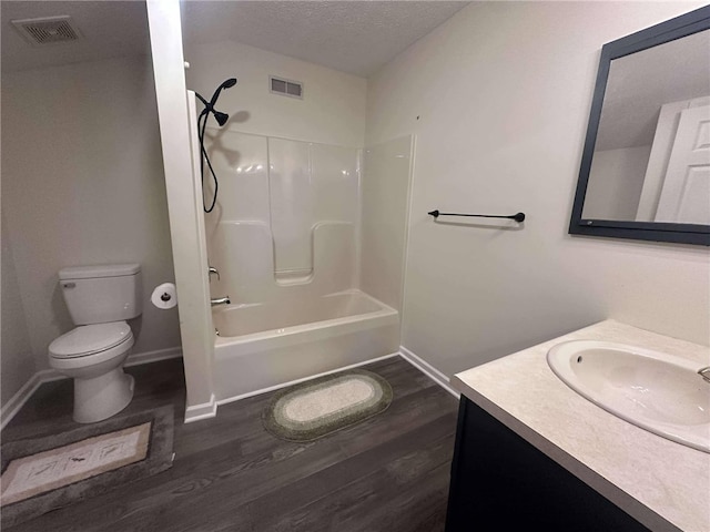 full bathroom featuring vanity, toilet, wood-type flooring, and a textured ceiling