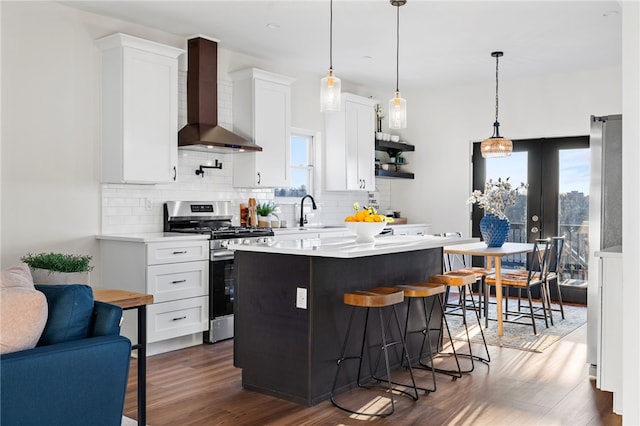 kitchen with white cabinetry, a kitchen island, wall chimney range hood, and stainless steel range with gas stovetop