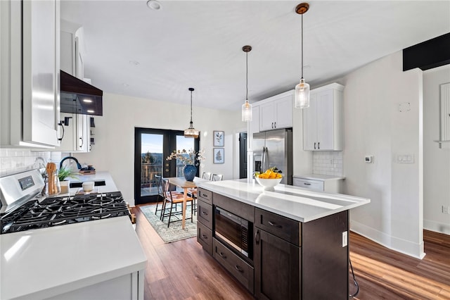 kitchen featuring stainless steel appliances, a center island, dark hardwood / wood-style floors, white cabinetry, and hanging light fixtures