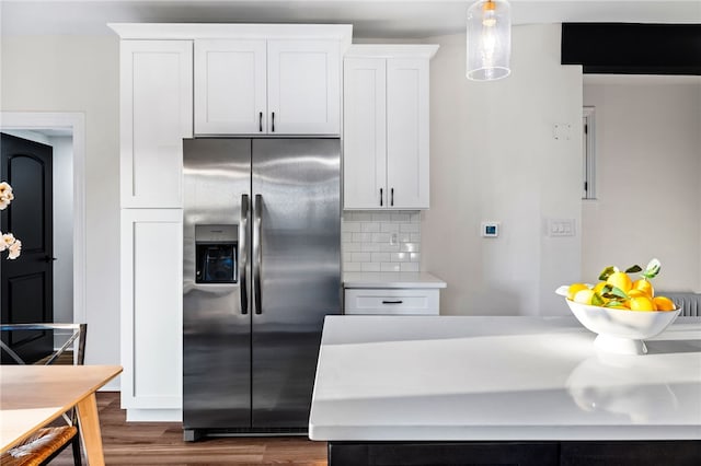 kitchen with decorative backsplash, dark hardwood / wood-style flooring, pendant lighting, white cabinets, and stainless steel fridge with ice dispenser