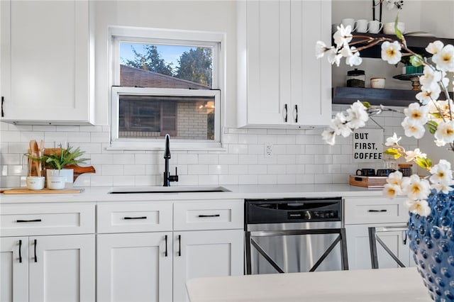 kitchen featuring stainless steel dishwasher, white cabinets, sink, and tasteful backsplash