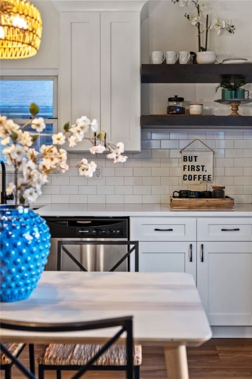 kitchen with decorative backsplash, white cabinetry, hardwood / wood-style floors, and stainless steel dishwasher