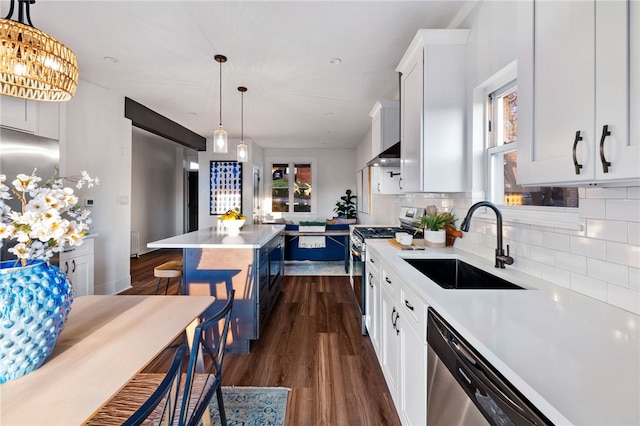 kitchen featuring white cabinets, sink, wall chimney exhaust hood, a kitchen island, and stainless steel appliances