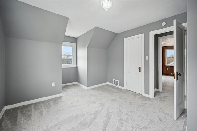 additional living space with light colored carpet and vaulted ceiling