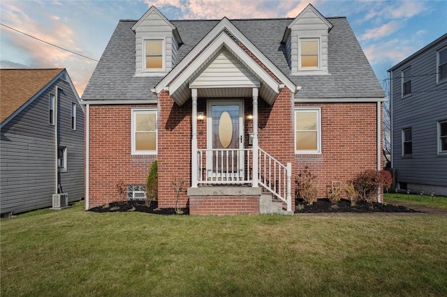 new england style home featuring central AC unit and a yard