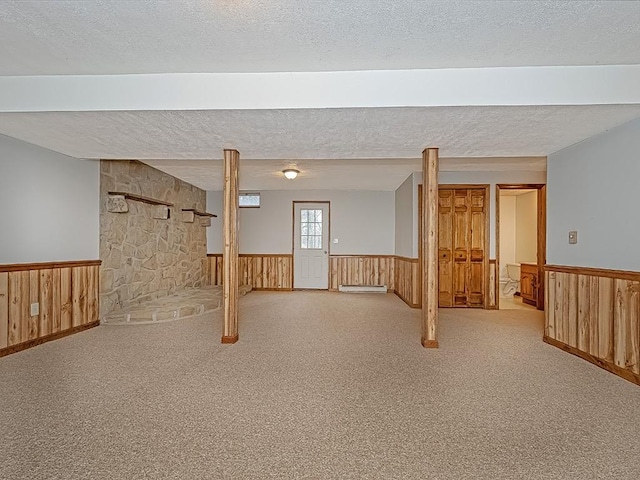 basement with a textured ceiling, light colored carpet, and wood walls