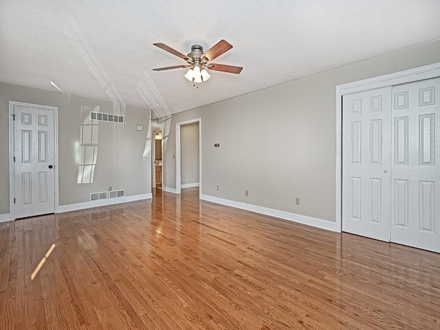 unfurnished living room with wood-type flooring, a textured ceiling, and ceiling fan