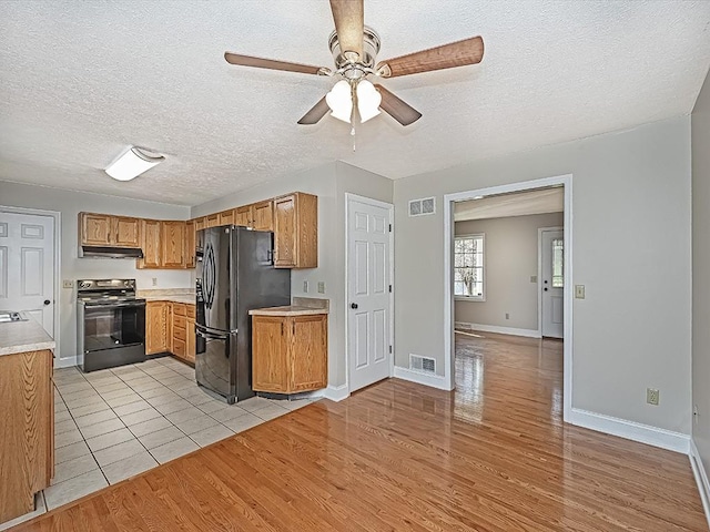 kitchen featuring light wood-type flooring, a textured ceiling, ceiling fan, sink, and black appliances