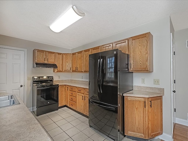 kitchen featuring black appliances, light tile patterned flooring, sink, and a textured ceiling