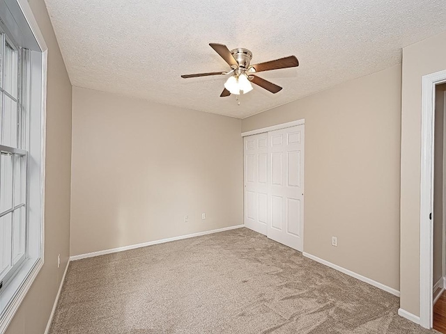 unfurnished bedroom with a textured ceiling, a closet, ceiling fan, and carpet floors