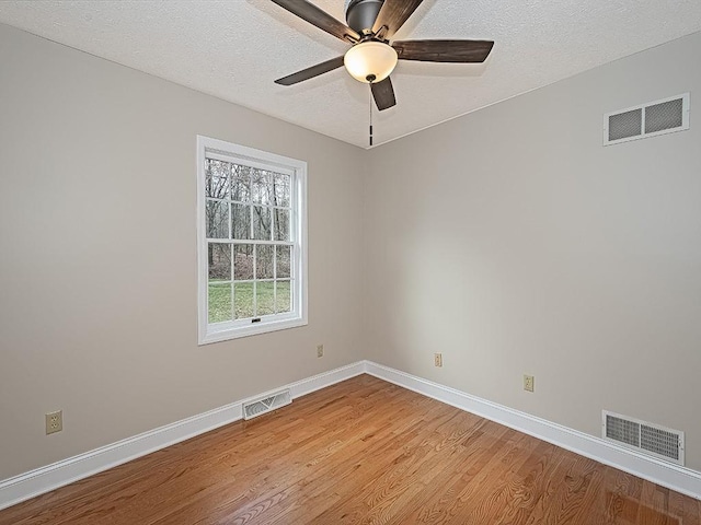 empty room with ceiling fan, light wood-type flooring, and a textured ceiling