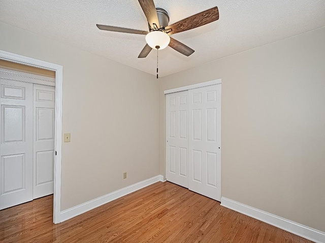 unfurnished bedroom with hardwood / wood-style floors, ceiling fan, a textured ceiling, and a closet