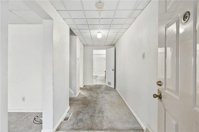 corridor with carpet flooring and a drop ceiling