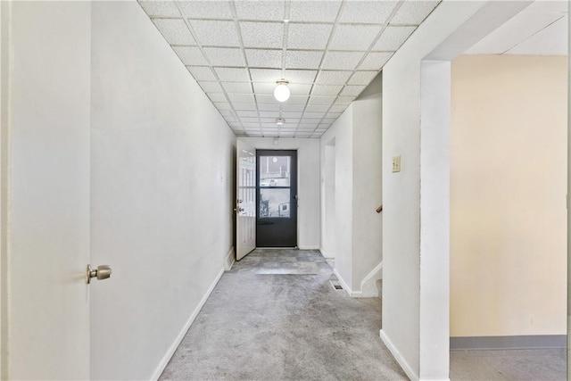 corridor with a drop ceiling and light carpet