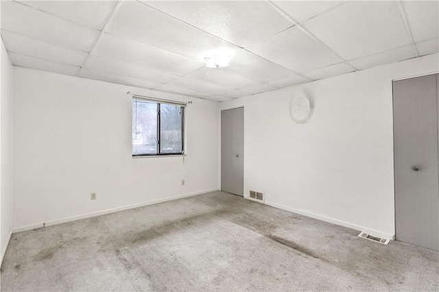 carpeted empty room with a paneled ceiling