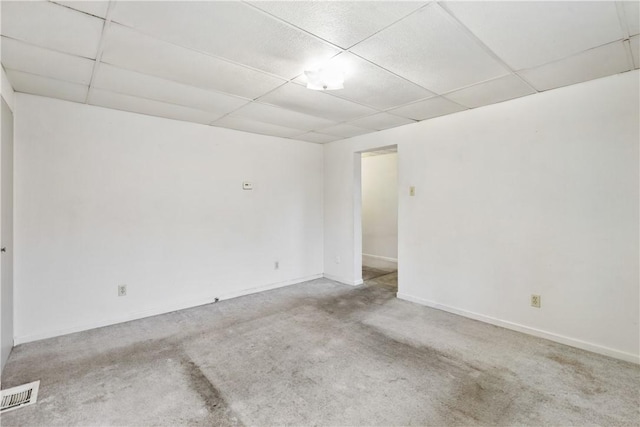 unfurnished room featuring carpet flooring and a drop ceiling