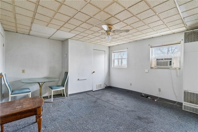 interior space with a drop ceiling, dark carpet, ceiling fan, and cooling unit