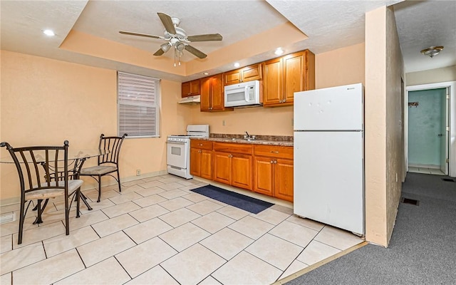 kitchen featuring ceiling fan, sink, a raised ceiling, white appliances, and light carpet