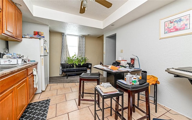 kitchen featuring ceiling fan, white fridge, light tile patterned floors, and a textured ceiling